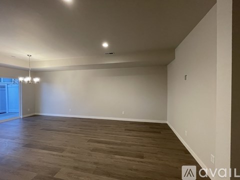 A spacious room with wooden flooring and white walls.
