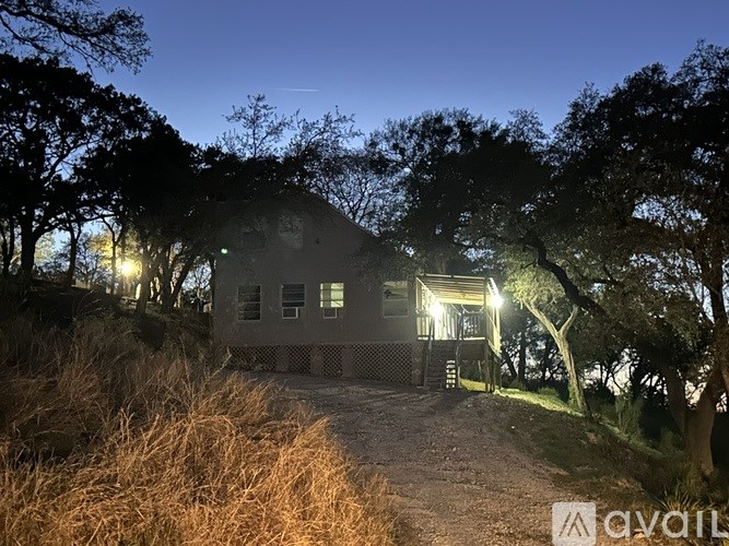 A house is lit up at night with trees in the background.