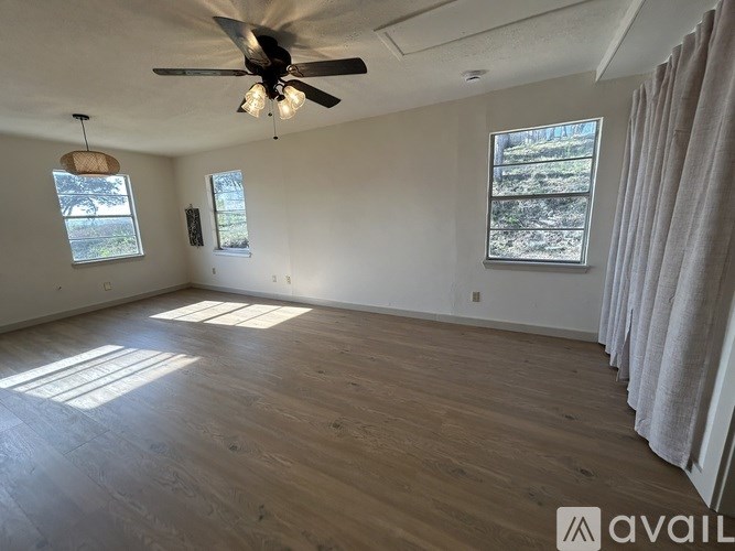 A room with a ceiling fan and two windows.