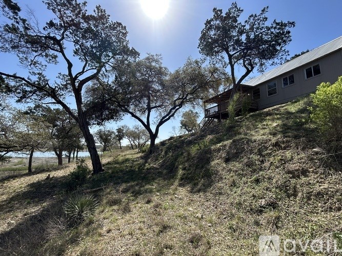 A house is situated on a hill with trees in front of it.