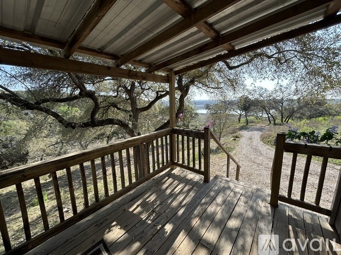 A wooden deck with a metal roof overlooks a dirt path through a wooded area.