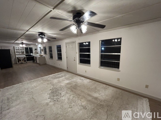 A room with a ceiling fan and a rug on the floor.