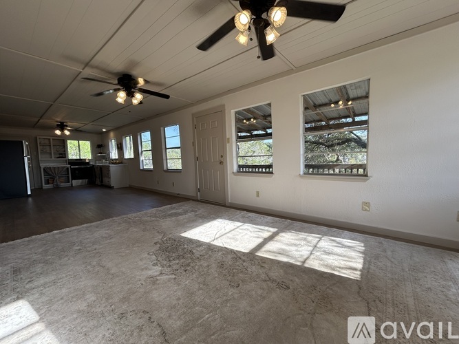 A spacious room with a ceiling fan and large windows.