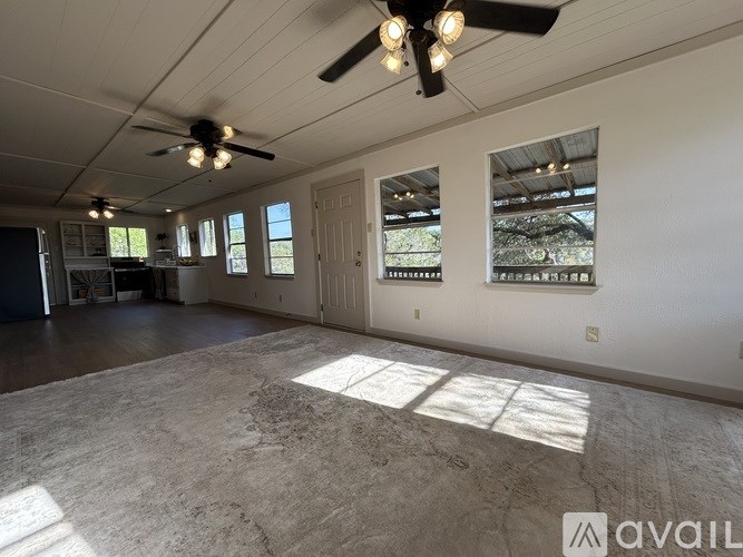 A spacious room with a ceiling fan and large windows.