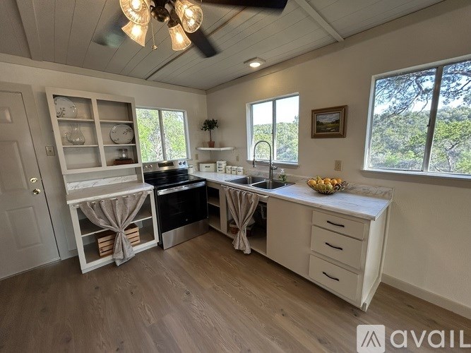 A kitchen with a ceiling fan and wooden flooring.