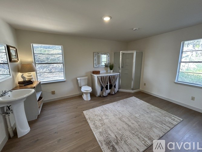 A bathroom with a toilet, sink, and window.