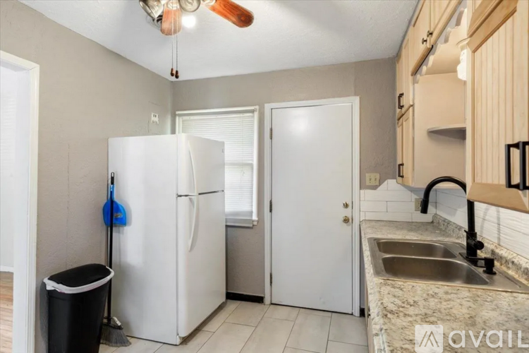 A kitchen with a white fridge, a sink, and a ceiling fan.