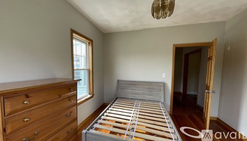 A bedroom with a bed, dresser, and window.