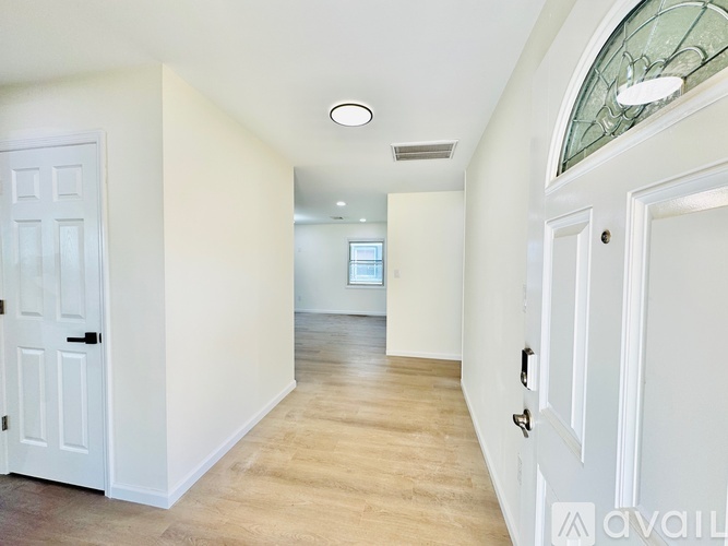 A hallway with white walls and a wooden floor.
