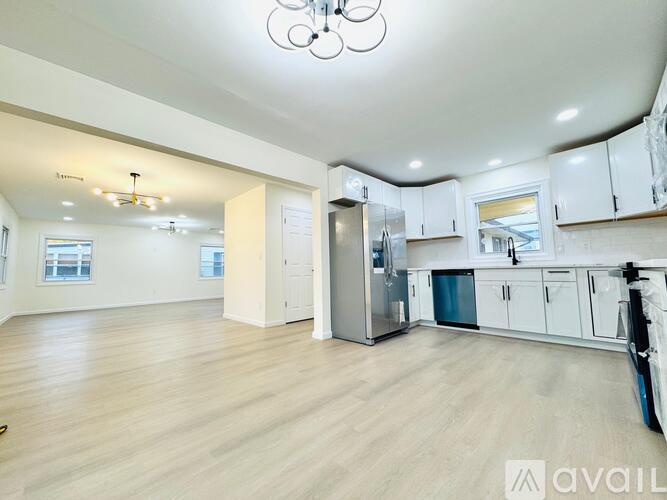 A spacious kitchen with white cabinets and a stainless steel refrigerator.