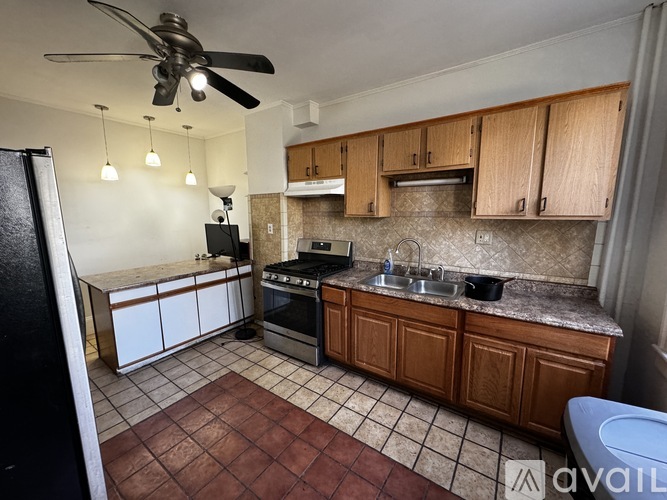 A kitchen with brown cabinets and a black refrigerator.