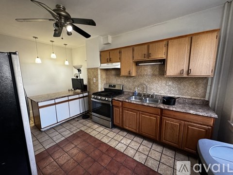 A kitchen with brown cabinets and a black refrigerator.