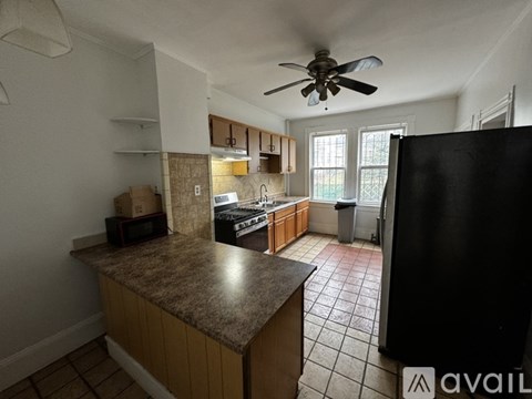 A kitchen with a black refrigerator and brown cabinets.
