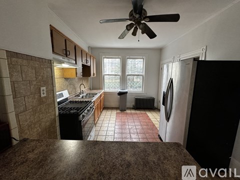 A kitchen with brown tiles and a fan.