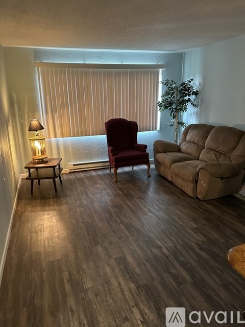 A living room with a red chair, a brown couch, and a lamp on a small table.