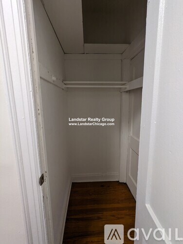 A small, empty room with wood flooring and white walls.