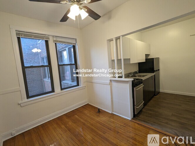 A well-lit, empty room with a kitchenette and a window.