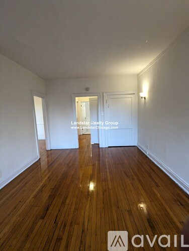 A room with wooden floors and white walls, with a door in the background.