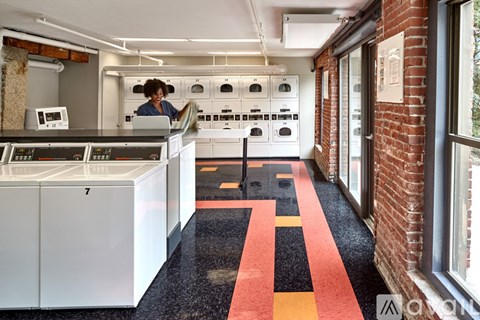 A woman is standing in a kitchen with white appliances and a red and black floor.