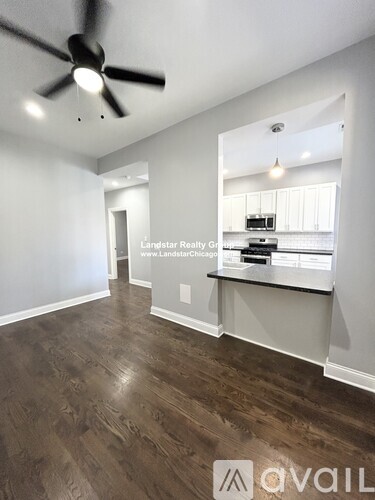 A room with a ceiling fan and wooden flooring.
