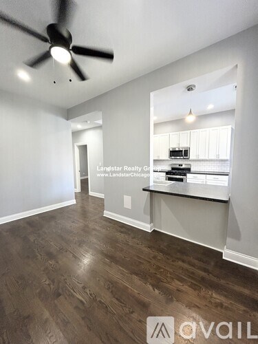 A room with a ceiling fan and wooden flooring.