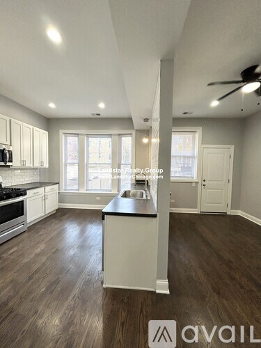 A kitchen with a wooden floor and white cabinets.