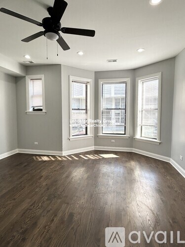 A room with a ceiling fan and wooden flooring.