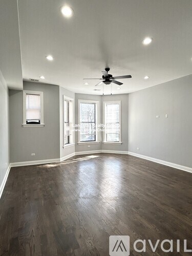A spacious room with a ceiling fan and large windows.