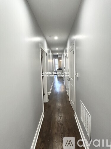 A long hallway with white walls and wood floors.