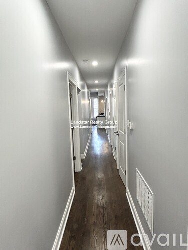 A long hallway with white walls and wood floors.