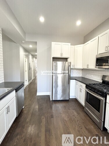 A kitchen with a stainless steel refrigerator and wooden floors.
