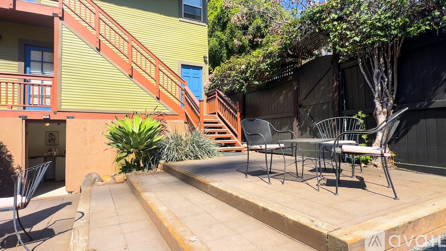 A patio with a table and chairs is in front of a green building.