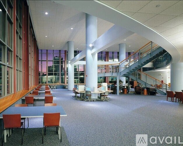A spacious atrium with tables, chairs, and a staircase.