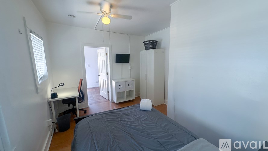 A bedroom with a bed, a ceiling fan, and a window.