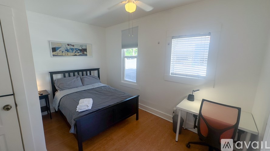 A bedroom with a bed, desk, and chair.