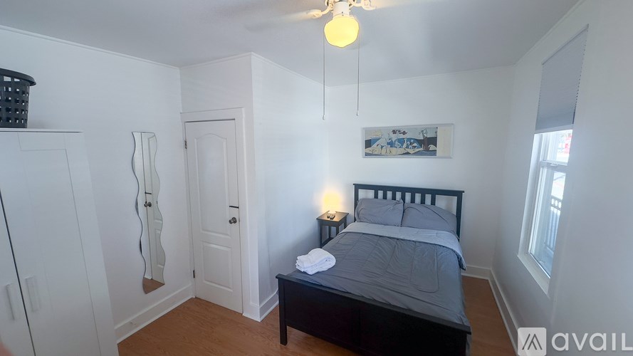 A bedroom with a bed, nightstand, and a painting on the wall.