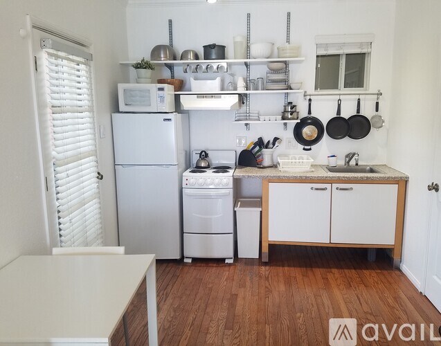 A kitchen with white appliances and wooden floors.
