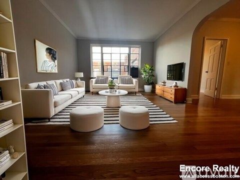 A living room with a white couch, a coffee table, and a large window.