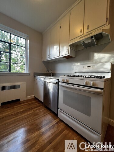 A kitchen with white appliances and wooden floors.
