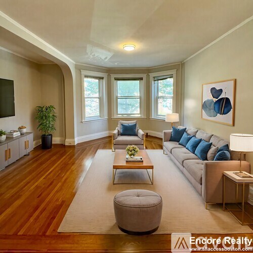 A living room with a grey couch, a coffee table, and a large window.