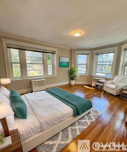 A bedroom with a large bed and a green throw blanket.
