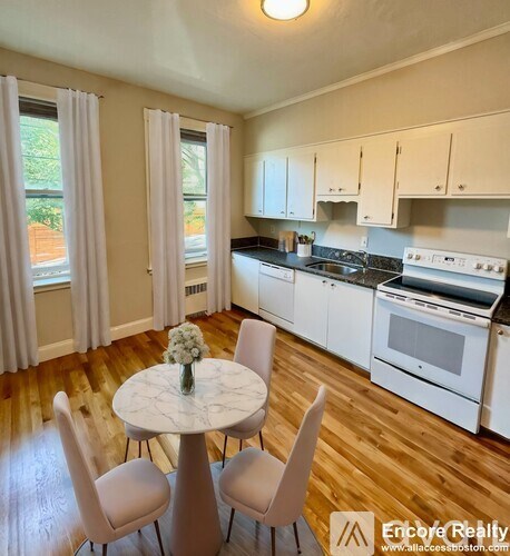 A kitchen with white cabinets and a round table with chairs.
