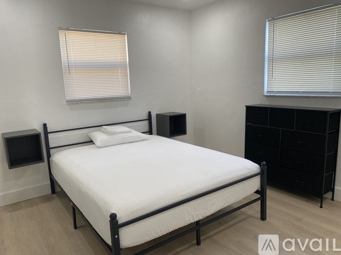 A bedroom with a white bed, black headboard, and a black cabinet.