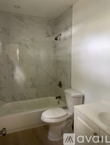 A bathroom with a marble tile wall and a bathtub.