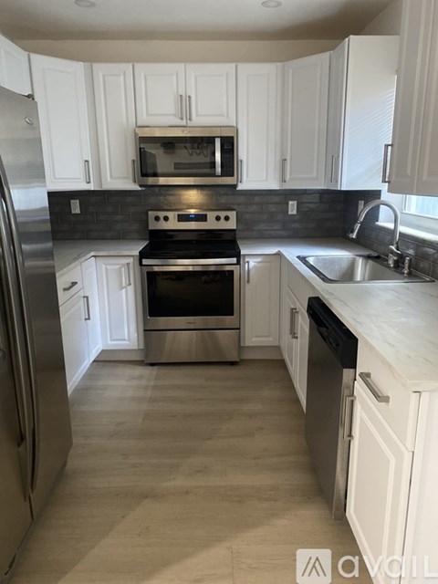 A kitchen with white cabinets and a stainless steel refrigerator.