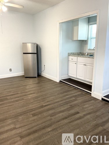 A kitchen with a stainless steel refrigerator and wooden flooring.
