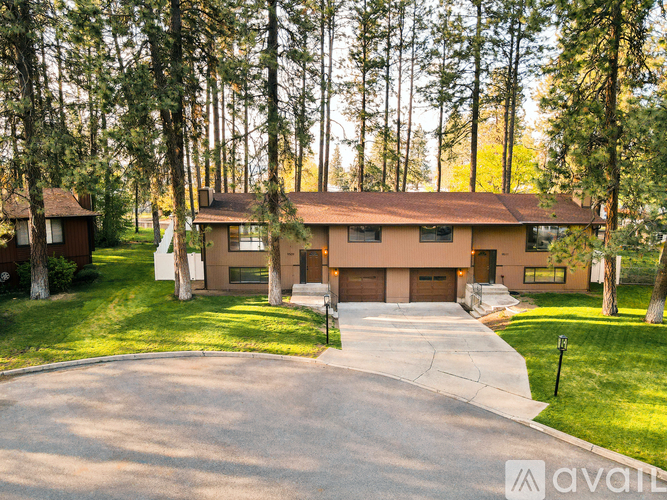 A house with a driveway in front of it surrounded by trees.