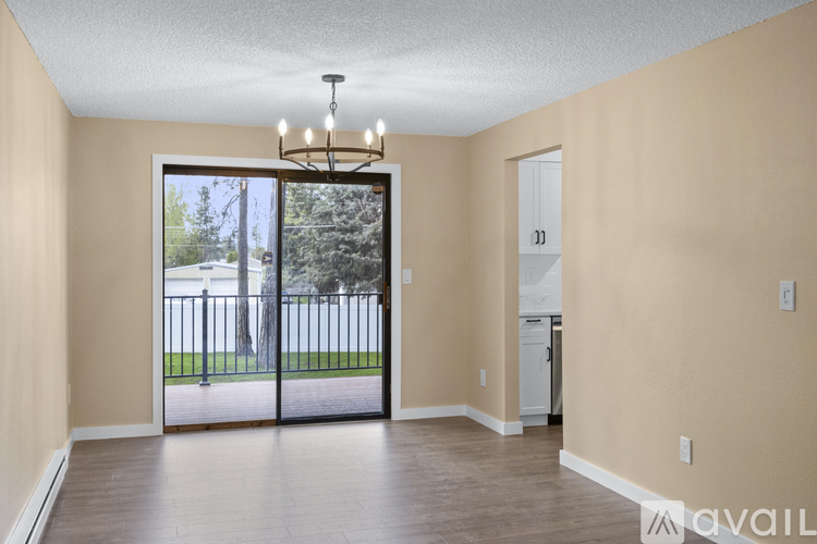 A room with beige walls and a wooden floor with a chandelier hanging from the ceiling.