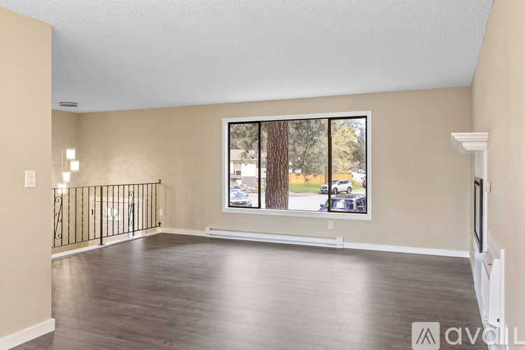 A spacious room with a large window and wooden flooring.