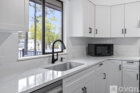 A kitchen with white cabinets and a black microwave.